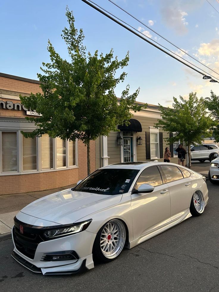 a silver car parked in front of a building on the side of a road next to trees