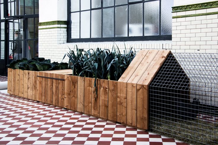 a wooden planter sitting on top of a checkered floor next to a building