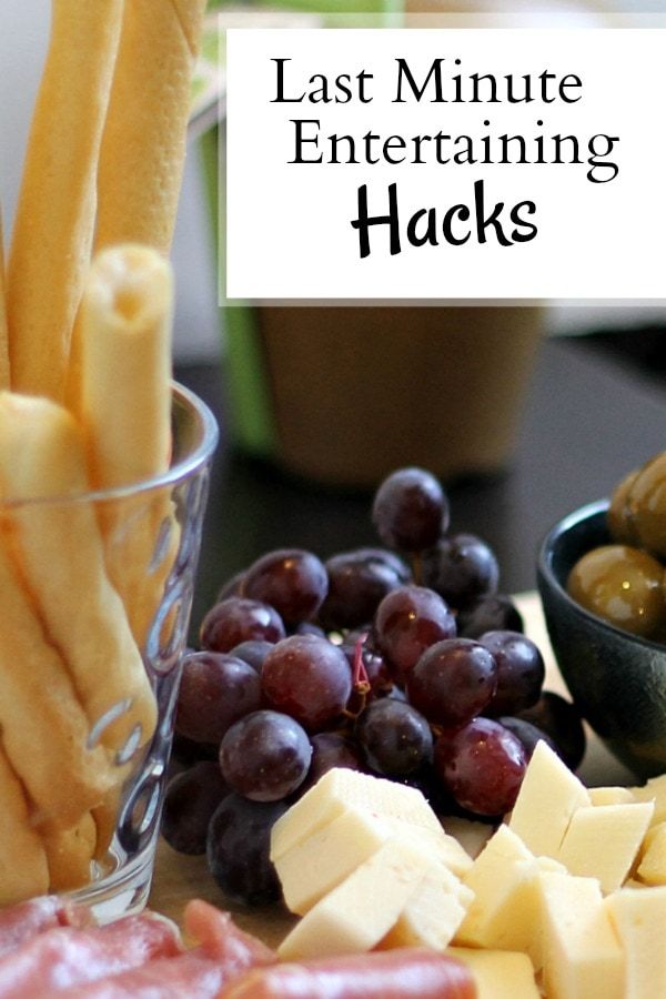 an assortment of cheeses, meats and grapes on a table with text overlay that reads last minute entertaining hacks