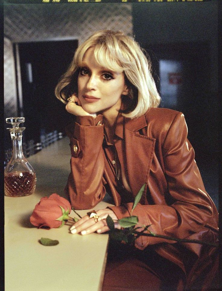 a woman sitting at a table with a flower in front of her and a vase behind her