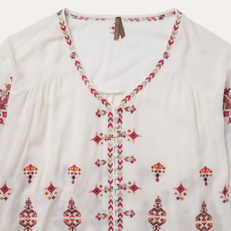 This top offers a soft and flowing silhouette with bohemian embroidered detailing throughout, including subtly hidden buttons at the front. A relaxed choice for brunch, a music festival, or wherever else the season takes you. 100% Viscose 3/4 Elastic Gathered Sleeves Curved Front and Straight Back Yokes Self-Covered Button Front Imported Bohemian V-neck Blouse With Embroidered Hem, Bohemian Long Sleeve Embroidered Top For Vacation, Bohemian V-neck Embroidered Top, Bohemian 3/4 Sleeve Summer Blouse, Bohemian Blouse With 3/4 Sleeves For Summer, Bohemian Spring Tops With 3/4 Sleeves, Bohemian Embroidered Relaxed Fit Blouse, Spring Bohemian Blouse With Embroidered Hem, Spring Bohemian Top With Embroidered Hem