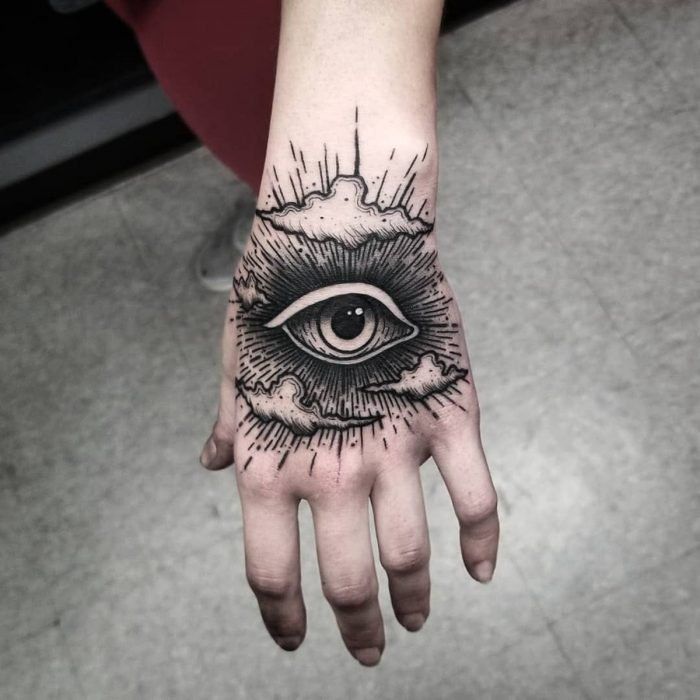 a hand with an all seeing eye tattoo on it