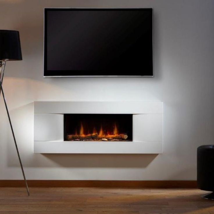 a white wall mounted fireplace with a flat screen tv above it and a black floor lamp next to it