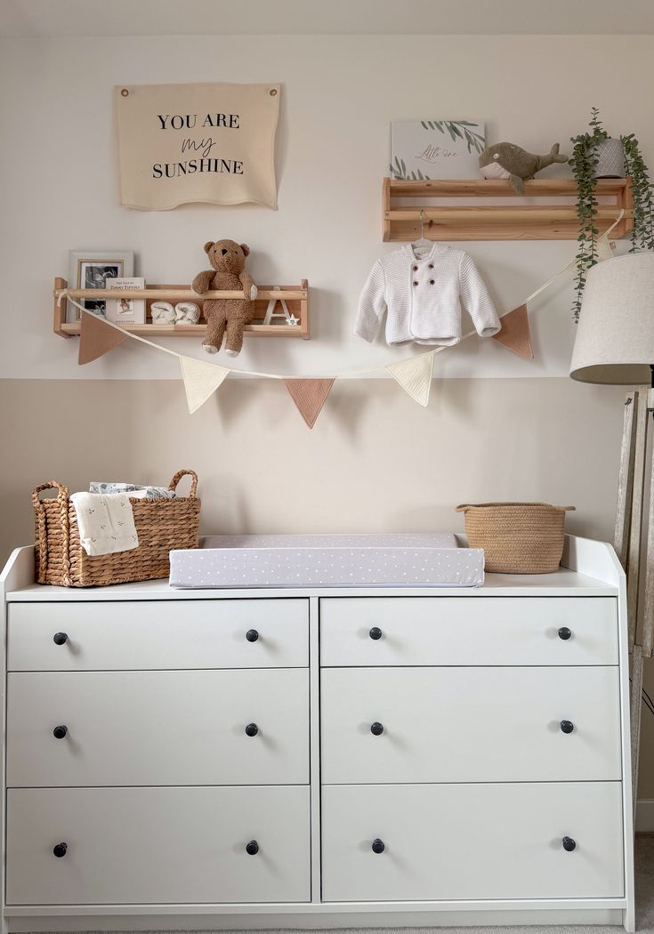 a baby's room with white dressers and toys on the shelves above them