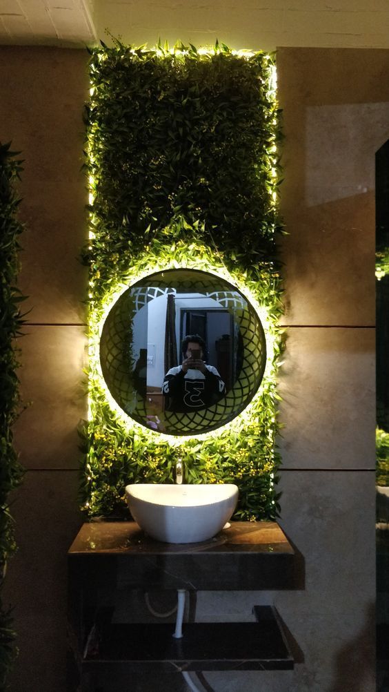 a bathroom with a round mirror on the wall and plants growing up to it's sides