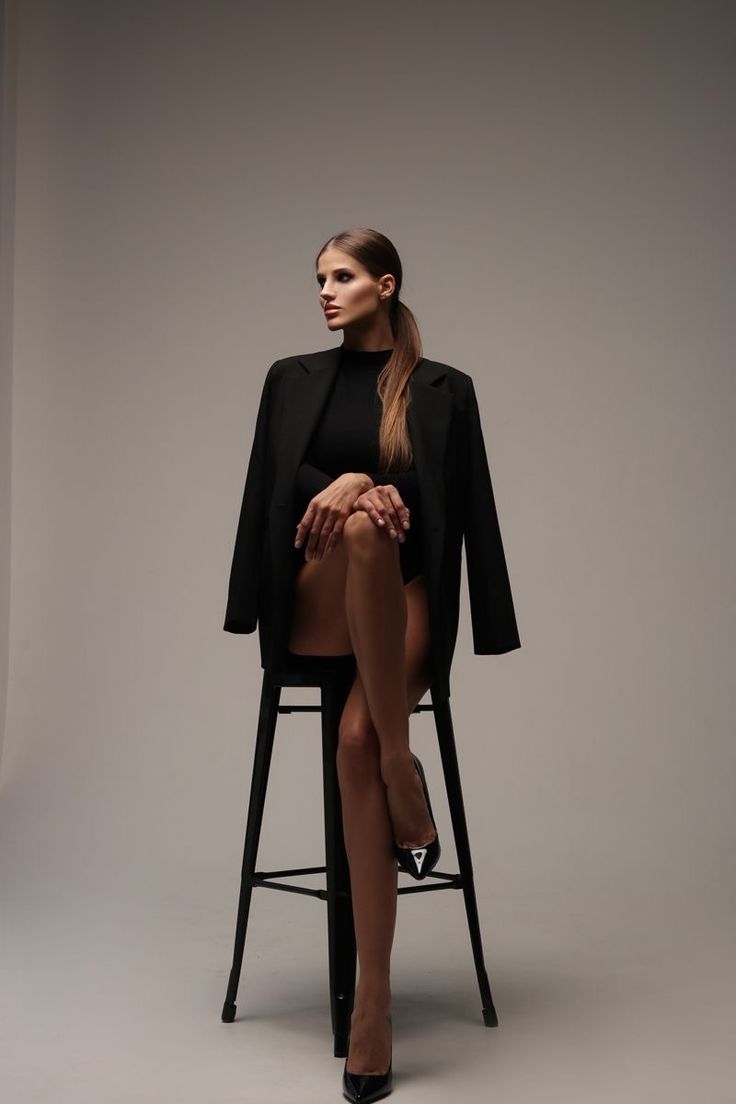 a woman sitting on top of a chair with her legs crossed