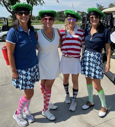 three women in matching outfits pose for a photo with their golf gear and hats on