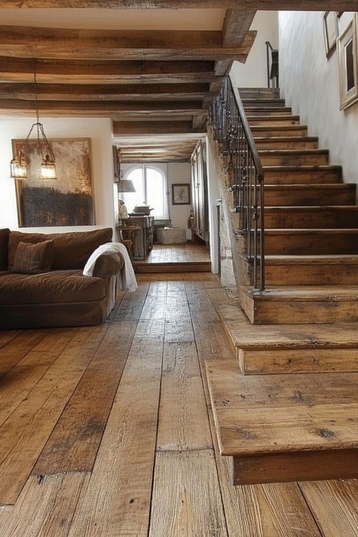 a living room filled with lots of furniture and wooden stairs leading up to the second floor