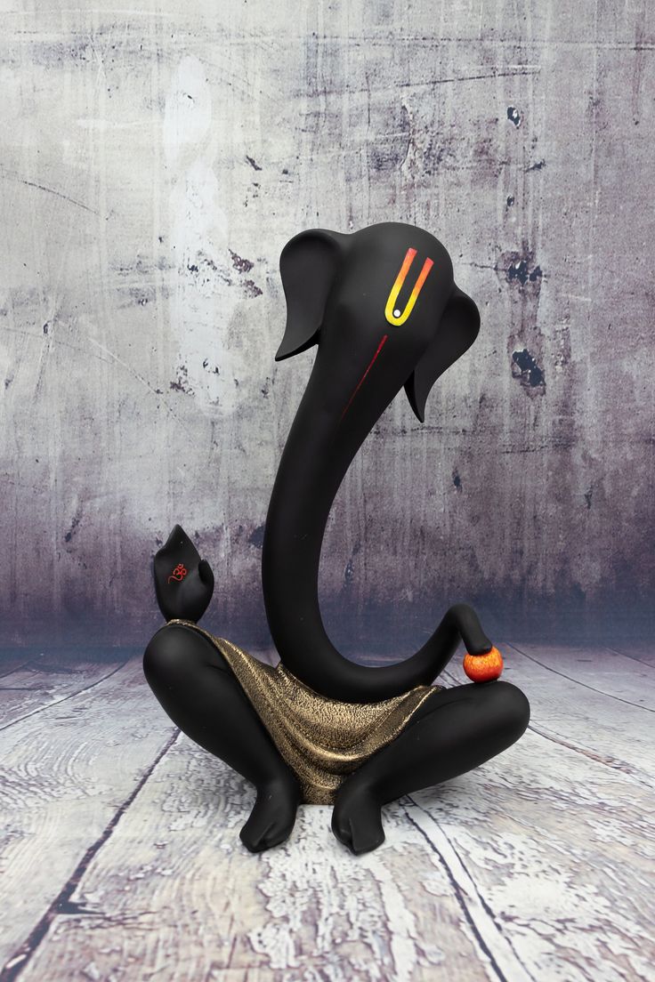 a black elephant statue sitting on top of a wooden floor next to a gray wall