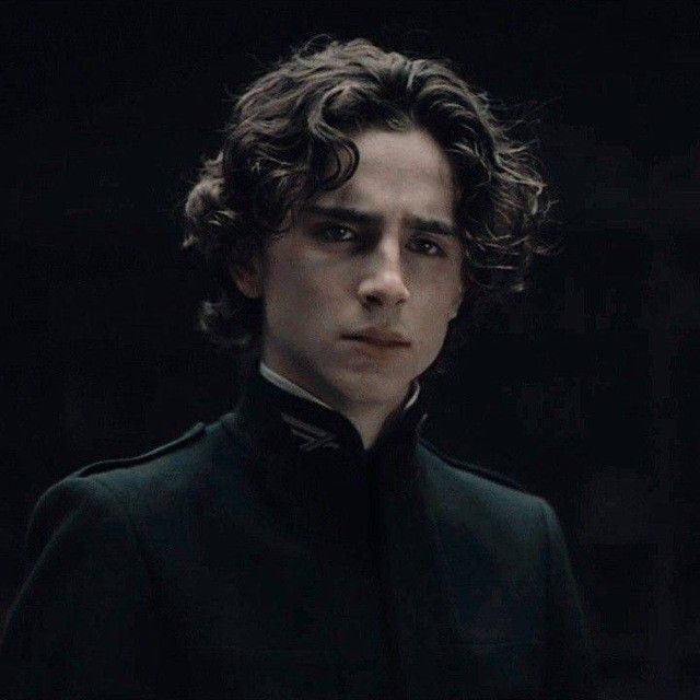 a man with curly hair wearing a black coat