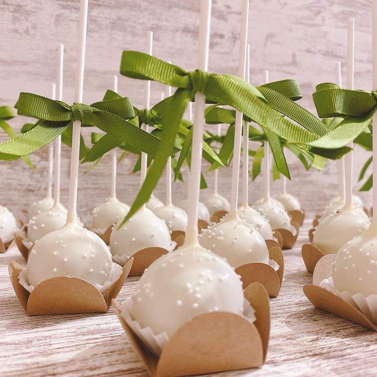 some cake pops with white frosting and green leaves on them are lined up in small boxes