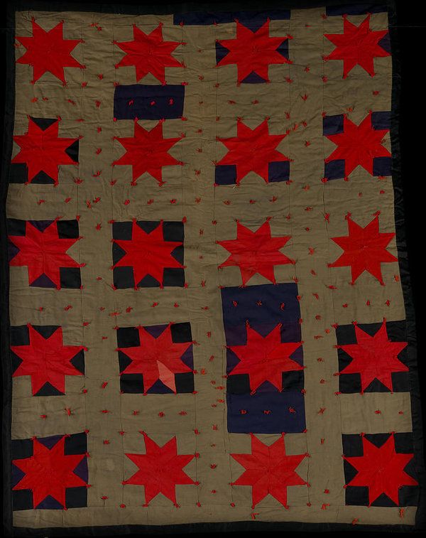 a quilt with red and blue stars on the front, along with black squares in the middle