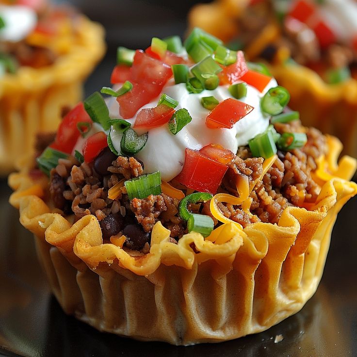 some taco salad cups are sitting on a table with other food in the background