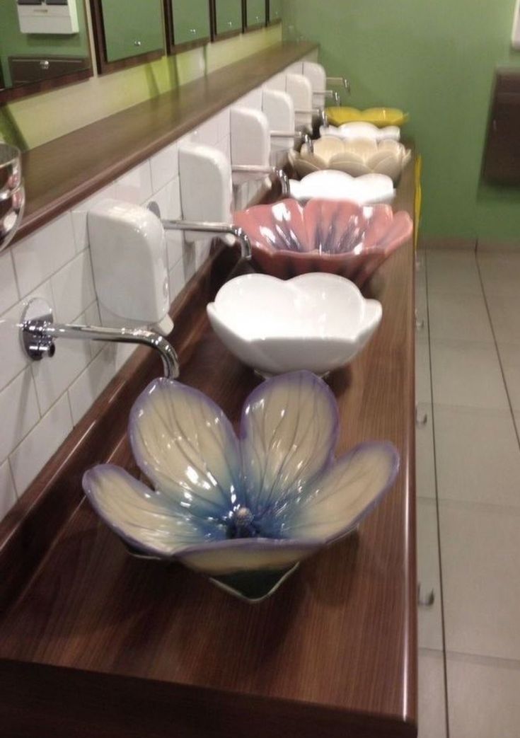 a row of bathroom sinks sitting on top of a wooden counter