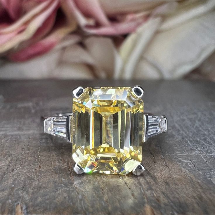 "The ring pictured is simulated diamond  #5731 -Approximate total carat weight:  4.00ctw diamond equivalent  -Center Stone Size:  10x8mm - approx. 3.50ct diamond equivalent -Center Stone Shape: emerald cut -Side Stones Size:  2 tapered baguettes - approximately 0.50ctw diamond equivalent -Gem Type:  simulated diamond -Stone Clarity: VVS1 -Stone Color: D -Moh's Scale: 8.5 hardness -Metal Type and Purity: 14k white gold -Setting: 4 prong basket head -Stock Ring Size: 6 -Country of Manufacturing: Yellow Diamond Ring With Baguette Cut, Yellow Diamond Baguette Cut Ring, Yellow Baguette Cut Diamond Ring, Yellow Baguette Cut Diamond Ring With Vvs Clarity, Classic Yellow Diamond Ring Baguette Cut, Gia Certified Yellow Baguette Cut Ring, Classic Yellow Baguette Cut Diamond Ring, Octagon Diamond Ring With Vs Clarity For Anniversary, Octagon Diamond Ring With Center Stone In Cubic Zirconia