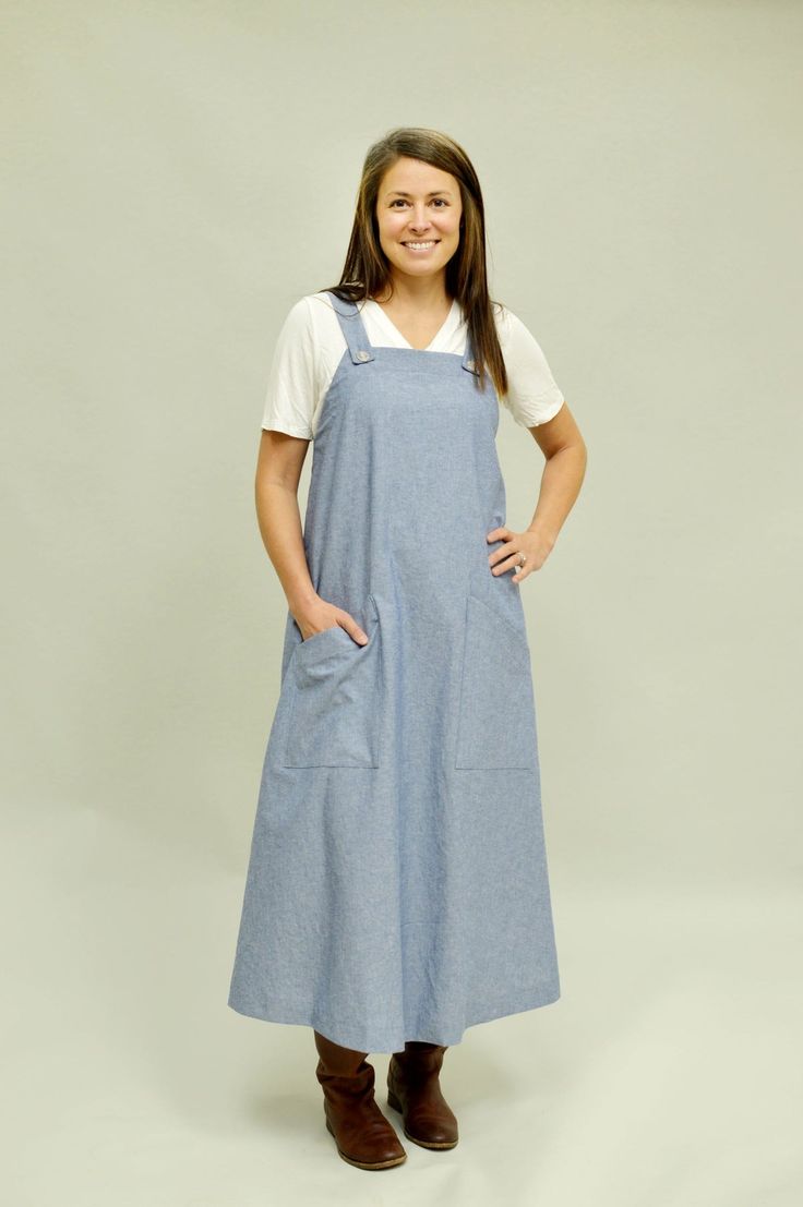 a woman standing with her hands on her hips wearing an apron and smiling at the camera