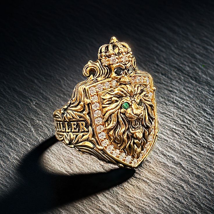 The King of Men's Gold Family Crest Rings Behold The King of Men's Gold Family Crest Ring, a majestic masterpiece that embodies power, legacy, and eternal strength. This extraordinary ring is more than just a piece of jewelry; it is a symbol of your regal heritage and indomitable spirit. Centerpiece Shield and Symbolism: At the heart of this majestic ring lies a shield adorned with a roaring lion head, symbolizing courage, nobility, and leadership. Crowning the lion is a skull, an emblem of impe Family Crest Ring, Lion Crest, Family Crest Rings, Eye Piercing, Roaring Lion, Ancient Kingdom, Mens Gold Rings, Black Fire, Diamond Eyes