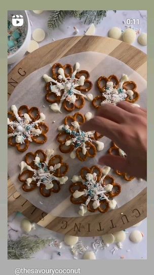 someone is decorating some pretzels on a wooden board with snowflakes