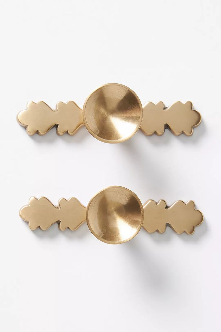 two metal spoons sitting next to each other on a white surface with gold colored handles