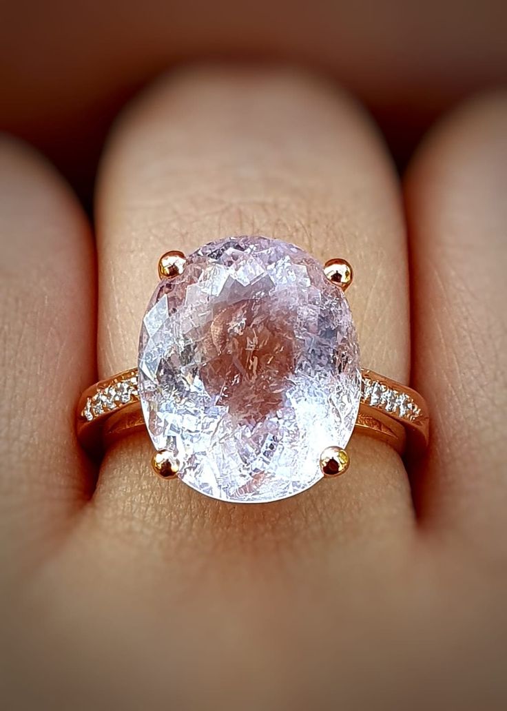 a woman's hand holding an engagement ring with a large pink diamond in it