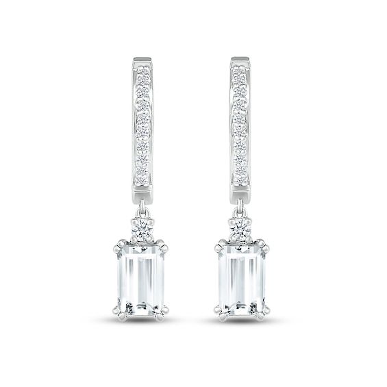 These mesmerizing earrings showcase a dangling emerald-cut white lab-created sapphire topped by a sparkling round white lab-created sapphire. The drop hangs from a sterling silver hoop adorned in more round white lab-created sapphires for all-over sparkle. The earrings secure with hinged backs. Modern Emerald Cut White Gold Earrings, Modern Baguette Cut White Diamond Earrings, Modern White Gold Emerald Cut Earrings, White Emerald Cut Baguette Diamond Earrings, Modern White Baguette Cut Diamond Earrings, White Gold Dangle Jewelry With Baguette Diamonds, White Gold Baguette Diamond Dangle Jewelry, Timeless White Diamond Dangle Earrings, White Emerald Cut Diamond Earrings With Accents