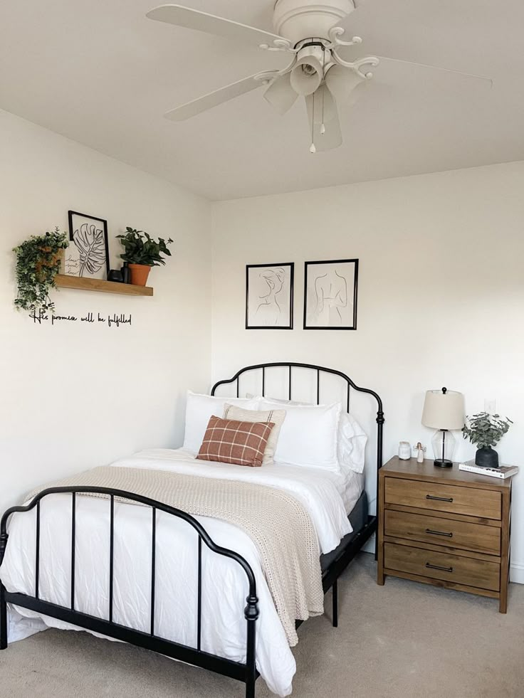 a bedroom with a bed, dresser and ceiling fan in the corner next to two framed pictures on the wall