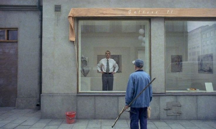 a man standing in front of a store window while holding a cane and looking at his reflection