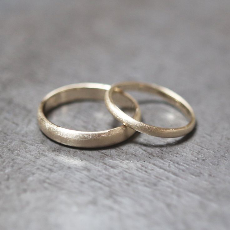 two gold wedding rings sitting on top of a table