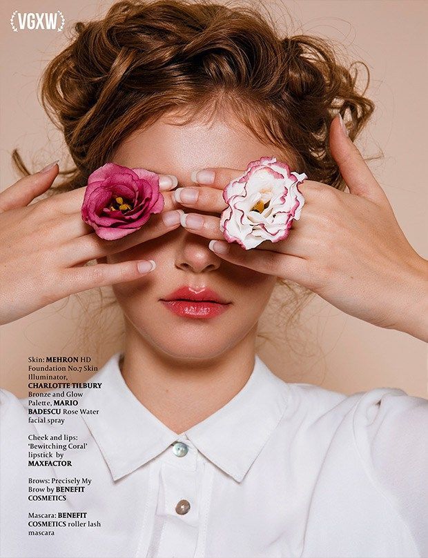 a woman holding two pink flowers over her eyes