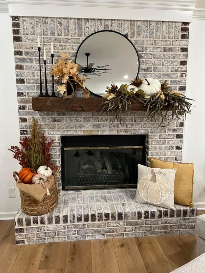 a living room filled with furniture and a fire place covered in pumpkins on top of a mantle