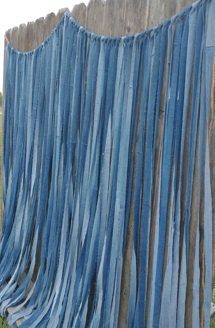 a fence with blue fabric hanging from it's sides and grass growing on the other side