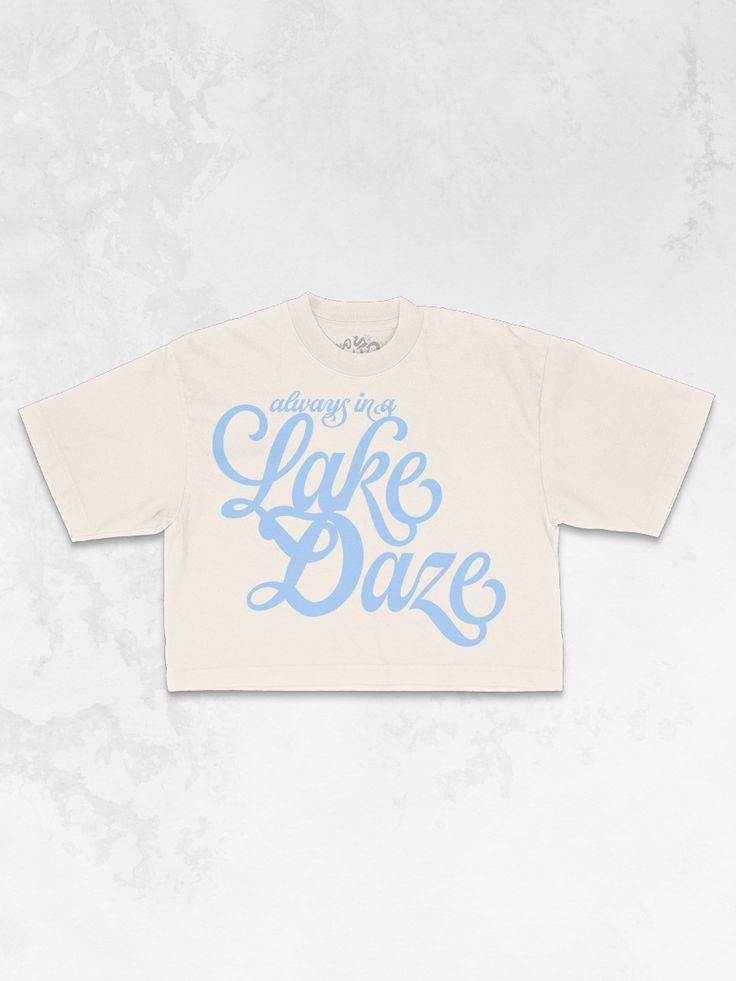 Get all of the summer-y vibes in our oversized retro inspired Lake Daze cropped t-shirt!- Features the phrase "Always in a Lake Daze" in a light blue ink - Screen print transfer that is heat pressed onto each tshirt - Tshirt is a high quality, garment dyed, vintage wash that gets softer after each wash - Oversized fit - Sizing translation: XS/S - M , S/M - L , L/XL - XL , 2XL/3XL - 2XL - 100% Cotton **due to screens & filters color may vary from pictures** Trendy Oversized Cropped T-shirt For Summer, Summer Graphic Tee Cropped T-shirt With Letter Print, Blue Graphic Print Crop Top T-shirt, Trendy Summer T-shirt With Lettering, Casual Summer T-shirt With Lettering, Summer Casual Cropped Shirt With Logo Print, Casual Cotton Cropped Shirt With Text Print, Casual Cropped Shirt With Logo Print For Summer, Summer Short Sleeve T-shirt With Lettering