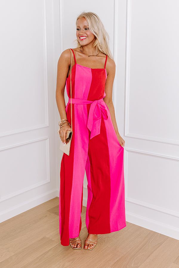 - Step into chic style with this jumpsuit! Its wide-leg silhouette gives it a trendy vibe. Cinched at the waist with a matching belt, it accentuates your figure while providing a flattering silhouette. Whether you are strolling along the boardwalk or attending a summer soirée, this jumpsuit is a chic choice that promises to stand out. - Panels of red and pink hued material - A built-in lining ending at upper-thigh length - A square cut neckline with an elastic back - Adjustable spaghetti straps Belted Jumpsuits And Rompers For Spring Vacation, Chic Belted Jumpsuits And Rompers For Spring, Spring Party Belted Jumpsuits And Rompers, Trendy Wide Leg Jumpsuits And Rompers For Day Out, Chic Belted Strapless Jumpsuit For Party, Summer Maxi Jumpsuits And Rompers With Tie Waist, Summer Maxi Length Jumpsuit With Tie Waist, Summer Maxi Length Jumpsuits And Rompers With Tie Waist, Spring Belted Jumpsuits And Rompers For Day Out