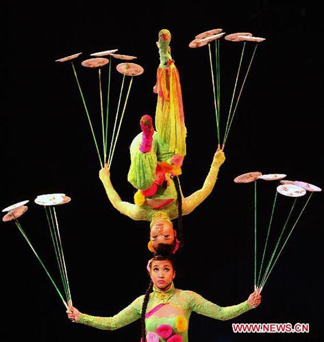 two women performing aerial acrobatic tricks on their heads and legs with flying discs in the air