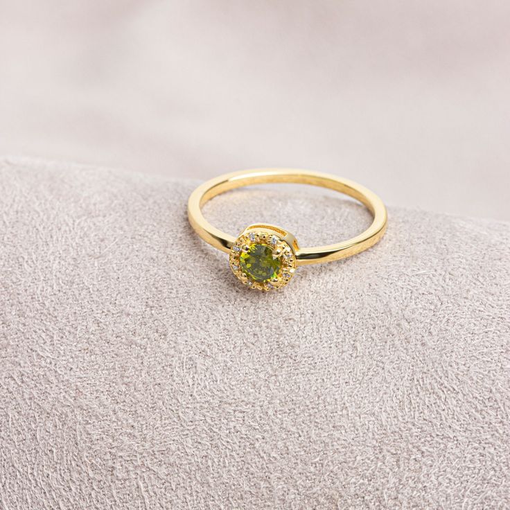 "Peridot: This stone, called the \"Emerald of the Night\" in ancient Egypt, is believed to protect the person using it like a shield. Our round cut ring with peridot stones surrounded by real diamonds is produced to always be with you. It can be given as a gift to yourself, your friends, your lover or your mother. Crown your happy days with our ring. We hope you create beautiful memories with our ring.   Peridot is the birthstone for those born in August. Don't forget to visit our store for all Green Diamond Halo Ring In Round Cut, Halo Diamond Ring For May Birthstone, Halo Design Diamond Ring For May Birthstone, Green Halo Promise Ring, Green Diamond Ring With Halo, Green Halo Ring With Round Band, Green 14k Gold Promise Birthstone Ring, May Birthstone Halo Ring For Promise, Green Halo Design Ring For May Birthstone