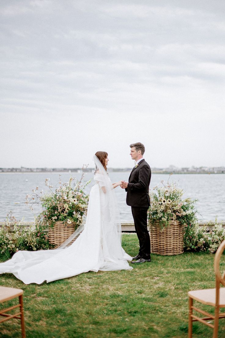 a bride and groom standing next to each other in front of the water on their wedding day