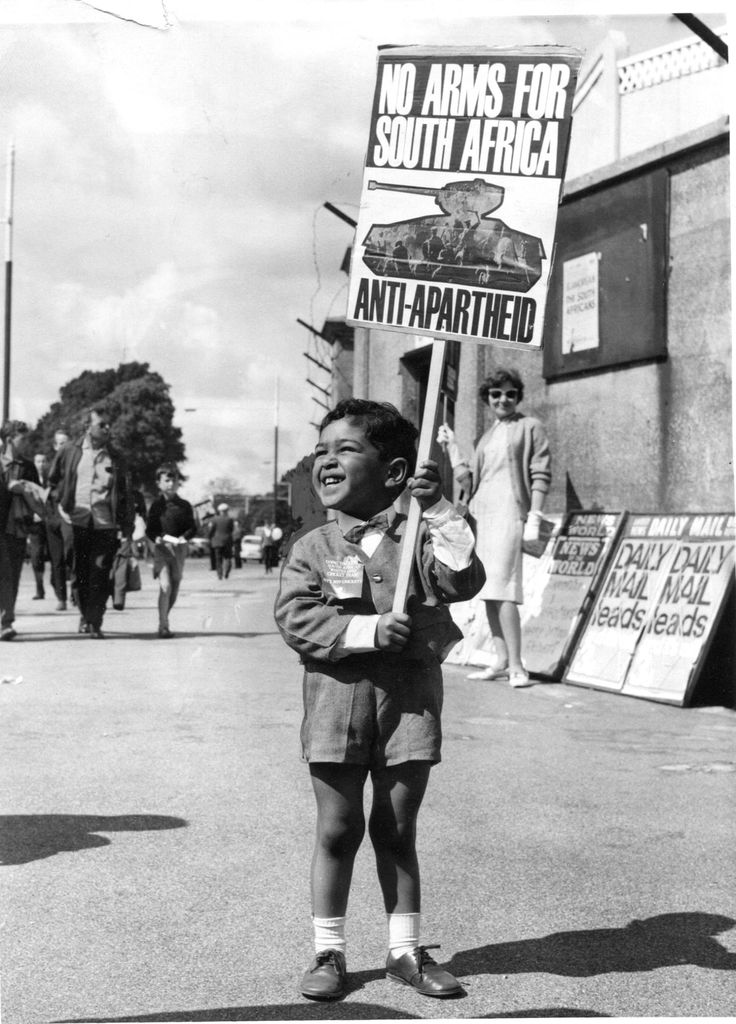 an old photo of a boy holding a sign that says no arms for south africa