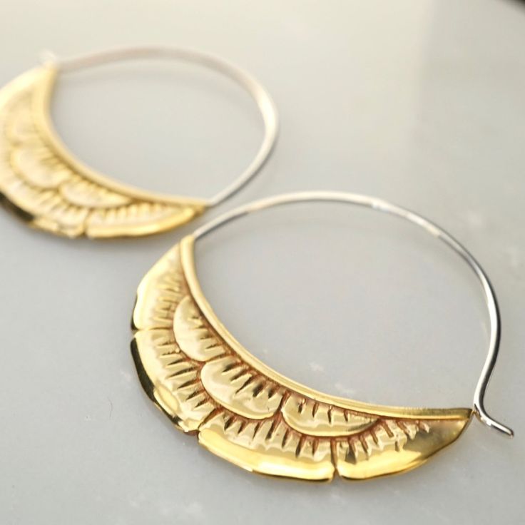 • Pair of Crescent Moon Flower Earrings. • 1.5 inch diameter hoops. • Flowers are crafted in solid artisan brass. • Ear-wire hoops are solid sterling silver. Detailed, handcrafted gold-tone flowers hang in a crescent moon shape. Each flower has depth and dimension and is crafted with the same detail on both sides of each earring. Flowers are solid Artisan Brass. Brass is a wonderful gold-tone metal. It can always maintain a beautiful high-shine with a quick polishing. Backings included. Handmade Gold Hoop Earrings In Sterling Silver, Unique Handmade Yellow Gold Hoop Earrings, Handmade Artisan Gold Hoop Earrings, Artisan Small Hoop Gold Jewelry, Artisan Gold Round Hoop Earrings, Gold Crescent Hoop Earrings With Ear Wire, Bohemian Gold Hand Forged Hoop Earrings, Artisan Gold Hoop Earrings, Artisan Gold Dangle Hoop Earrings