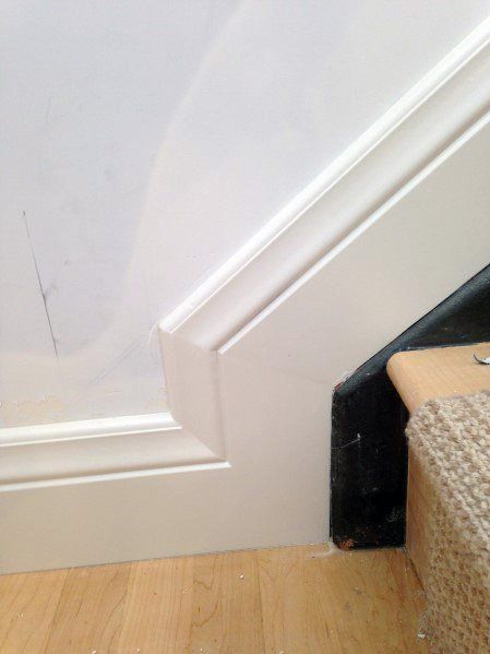 the corner of a room that has been painted white and is next to a carpeted stair case