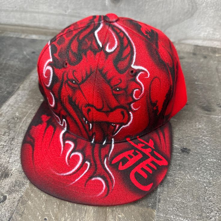 This is an airbrushed snapback hat featuring a Red Dragon design.  The Calligraphy on the hat reads "dragon". This hat is adjustable and will fit almost anyone.  These hats are waterproof and can withstand a good soaking but they should not be washed in a washing machine or dish washer.  Thank you, Brad.  Shipping is free for this item anywhere in the US. Red Fitted Hat With Flat Crown For Streetwear, Red Flat Brim Fitted Hat For Streetwear, Red Fitted Cap For Streetwear, Red Hip Hop Fitted Hat For Streetwear, Red Fitted Hat With Curved Brim For Streetwear, Red Hip Hop Fitted Hat With Flat Bill, Red Hip Hop Snapback Hat, Red Hip Hop Hat, One Size Fits Most, Red Hip Hop Hat One Size Fits Most