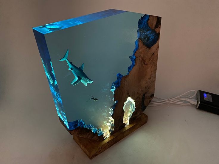 an illuminated box with two sharks swimming in the water