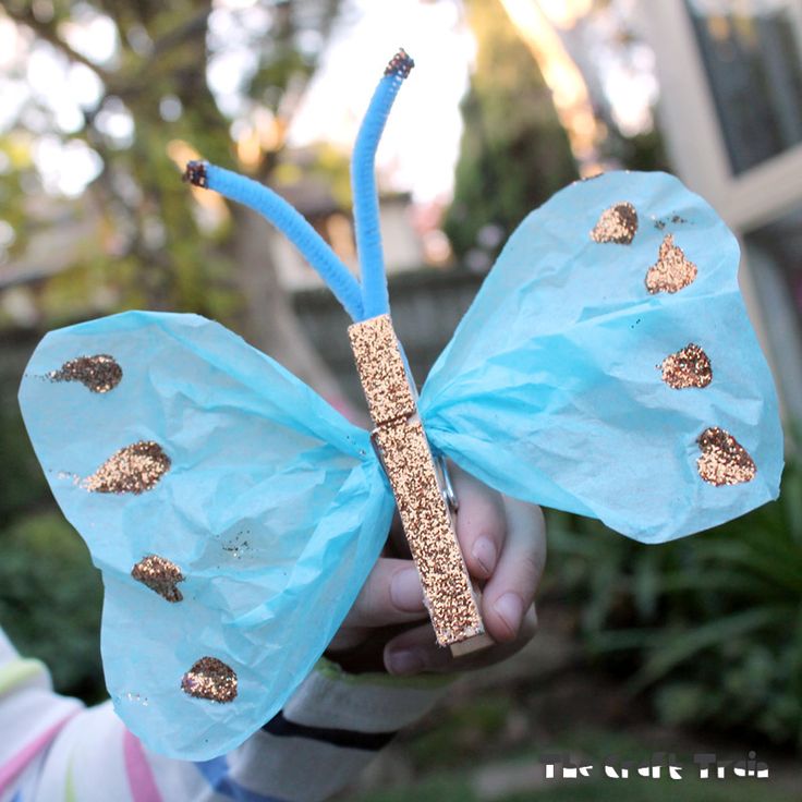 a child holding a paper butterfly with gold glitters on it