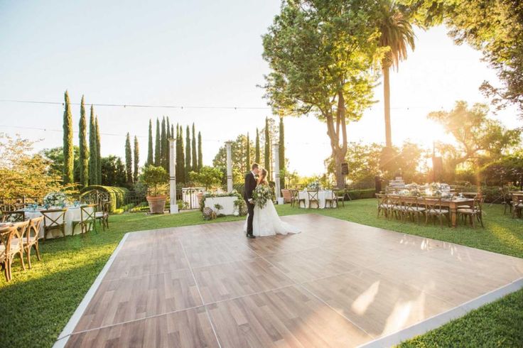 a bride and groom standing on a dance floor in the middle of an outdoor venue