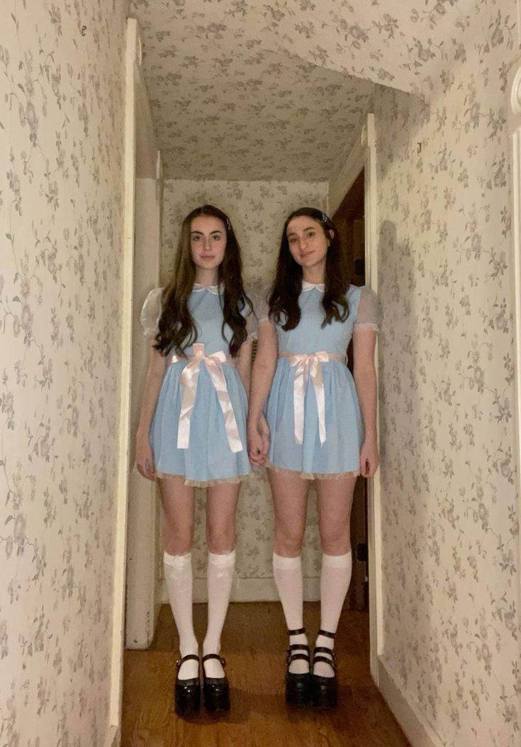 two young women dressed in short blue dresses and white socks are standing next to each other