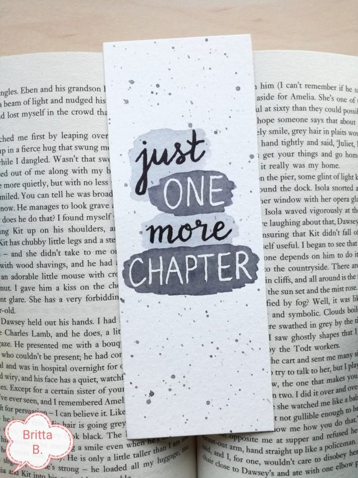 a bookmark with the words just one more charter on it, sitting in front of an open book