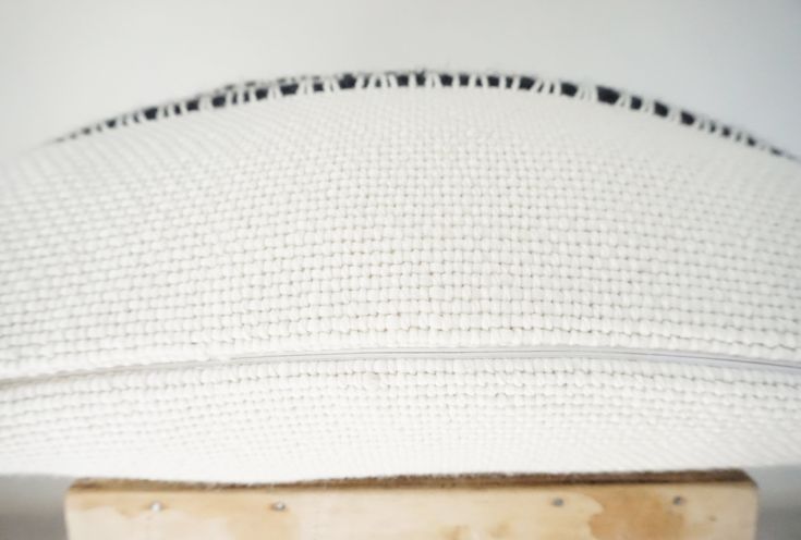 a close up view of a white cushion on a wooden stand with black dots and lines