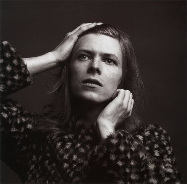 a black and white photo of a woman with her hands on her head, looking off to the side