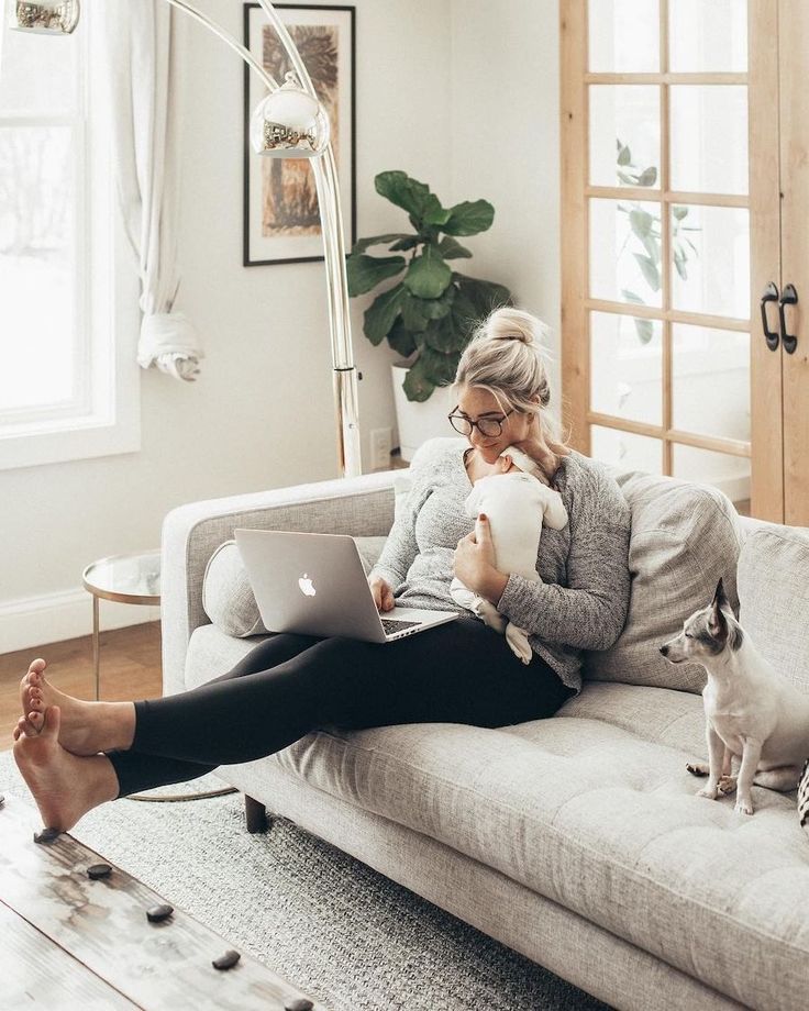 a woman sitting on a couch with her dog and laptop