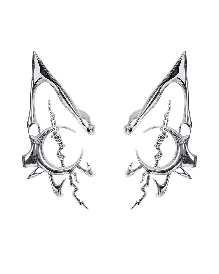 two pairs of silver earrings with spikes on each side and an eye shaped design in the middle