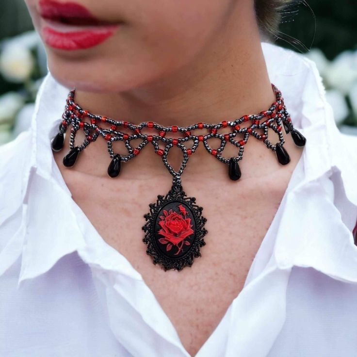 "Here is a choker that is truly captivating - a masterpiece that effortlessly combines the vintage allure of yesteryears with a touch of modern elegance. Behold, the centerpiece of this conversation: a Gothic-style choker that beckons with its unique charm. Picture a red rose, vivid and striking, set against an enigmatic black background, forming an intricate cameo. This captivating piece is cradled within a gunmetal setting, designed to mesmerize anyone who sets their gaze upon it. What sets th Vintage Red Choker For Party, Vintage Choker As Valentine's Day Gift, Vintage Choker Jewelry For Valentine's Day, Elegant Rose Design Jewelry Choker, Elegant Rose Design Choker Jewelry, Vintage Red Choker Jewelry, Red Vintage Choker Jewelry, Vintage Red Choker Necklace, Red Vintage Choker Necklace